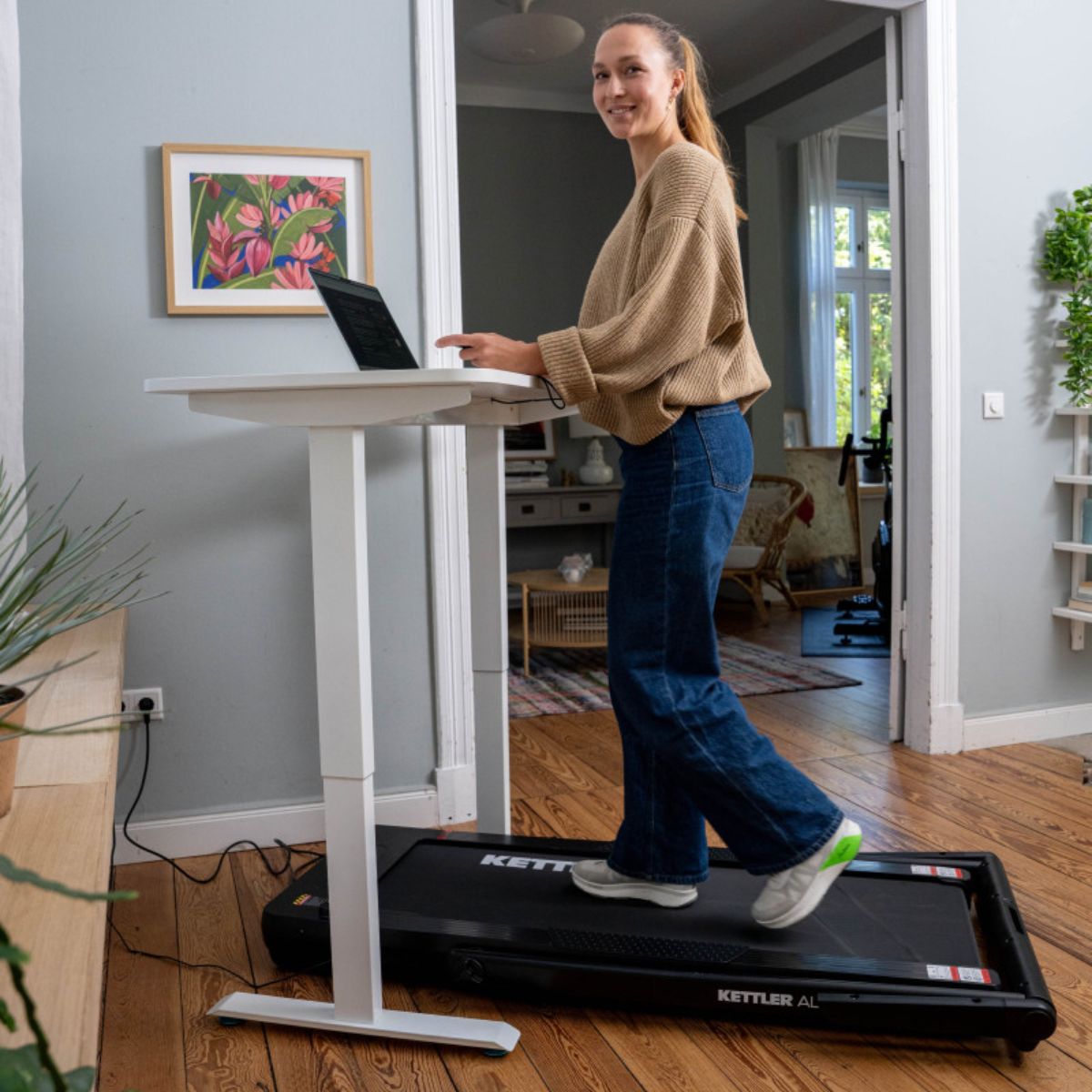 Moteris eina KETTLER Alpha Walk 400 takeliu dirbdama prie reguliuojamo auk&scaron;čio stalo
